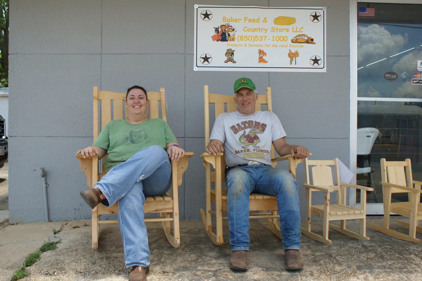Jennifer Augustine and Tony Happel sitting in wooden rocking chairs outside Baker Feed & Country Store.